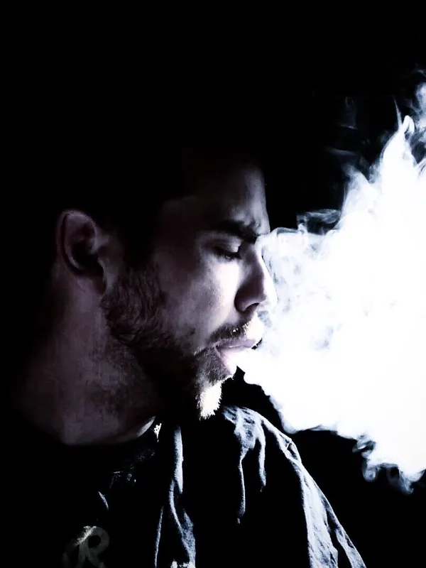 TaskRok in profile, exhaling a cloud of vapor against a black background